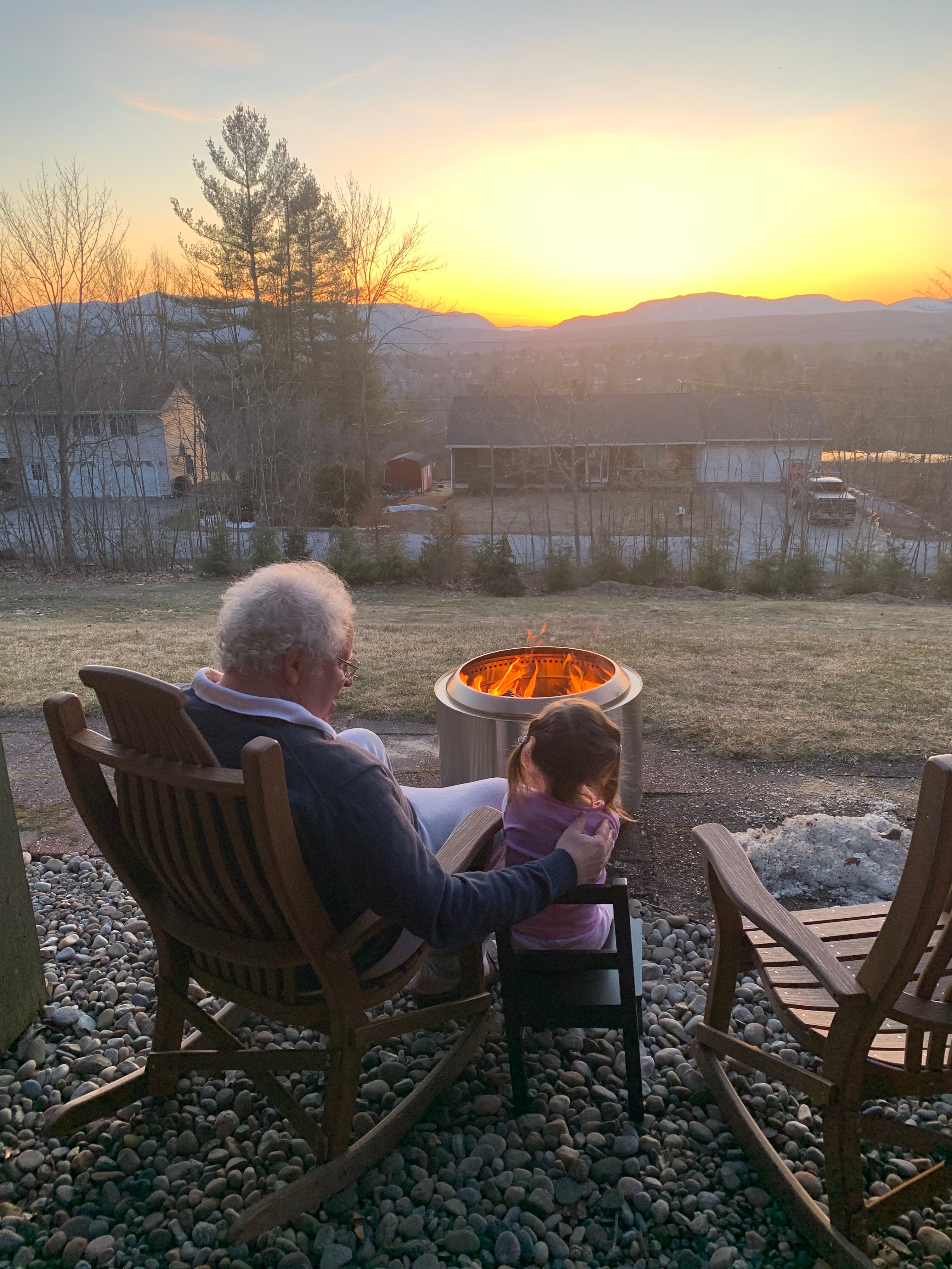 Dave Wolk and his granddaughter Dahlia by the fire, watching the sun set over the Rutland valley from their home.