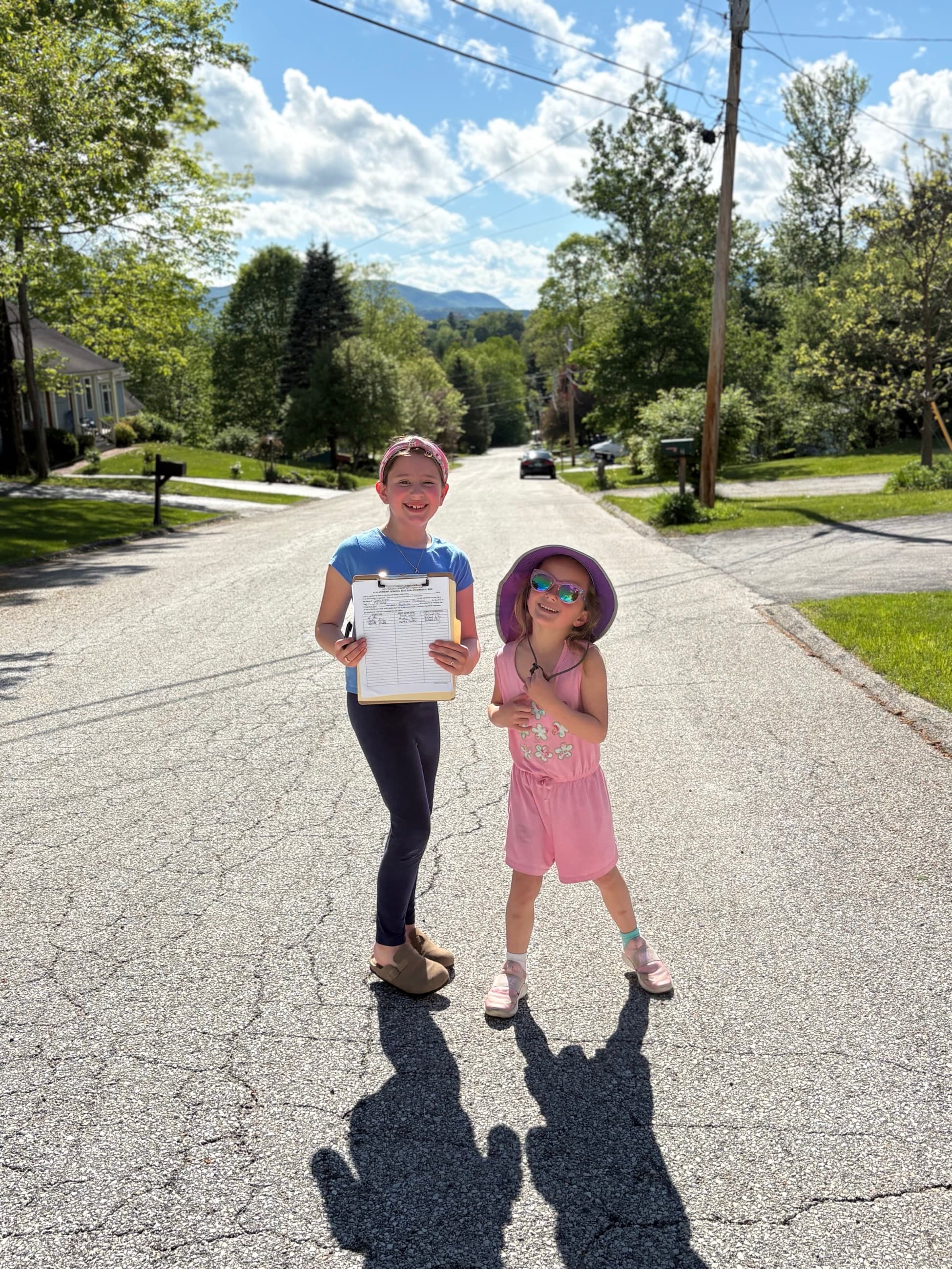 Dave Wolk's two young granddaughters standing in their Rutland neighborhood street, one holding a clipboard of petition signatures.