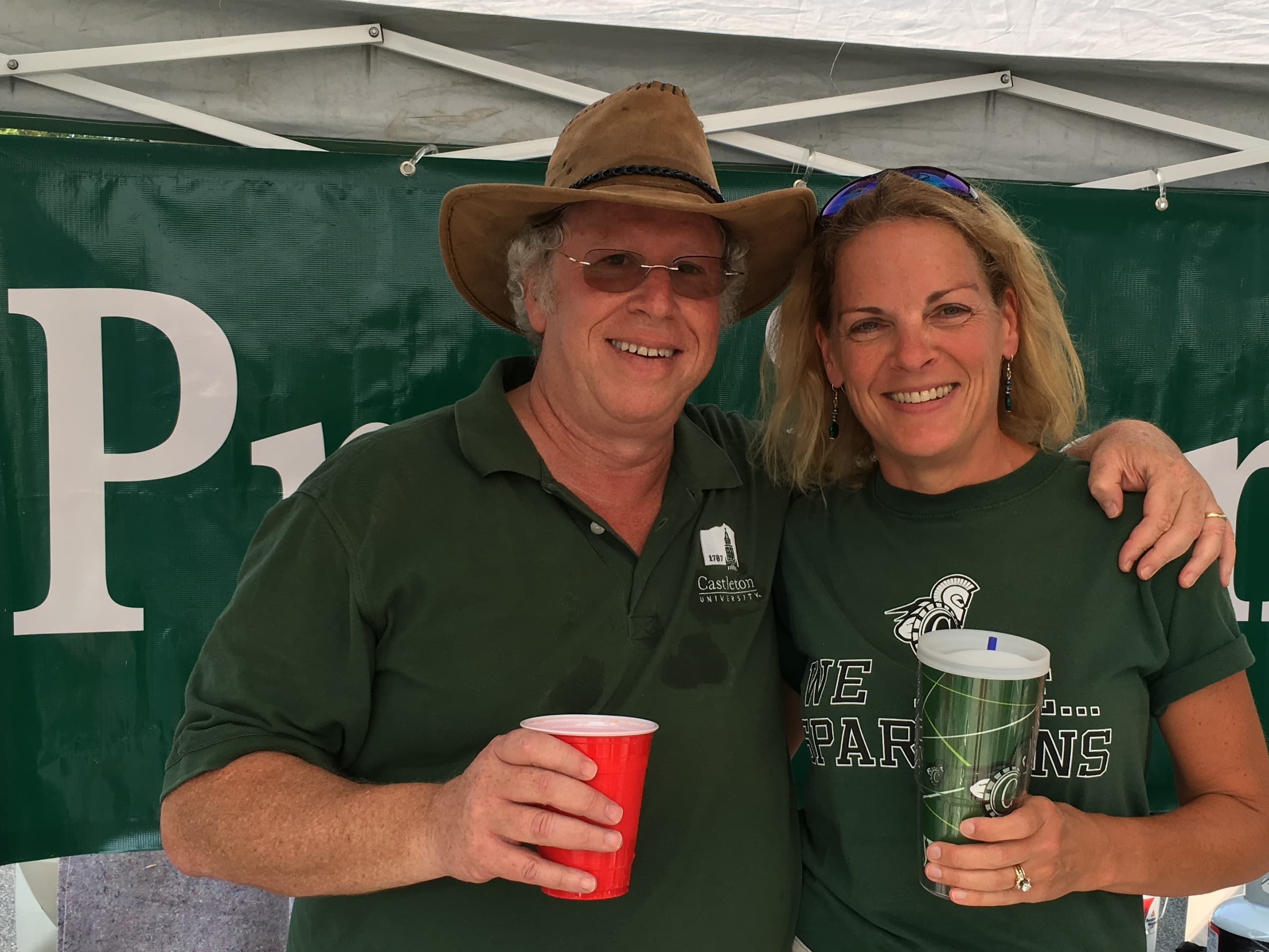 Dave Wolk and his wife Lyn at a Castleton tailgate, in front of the President banner.