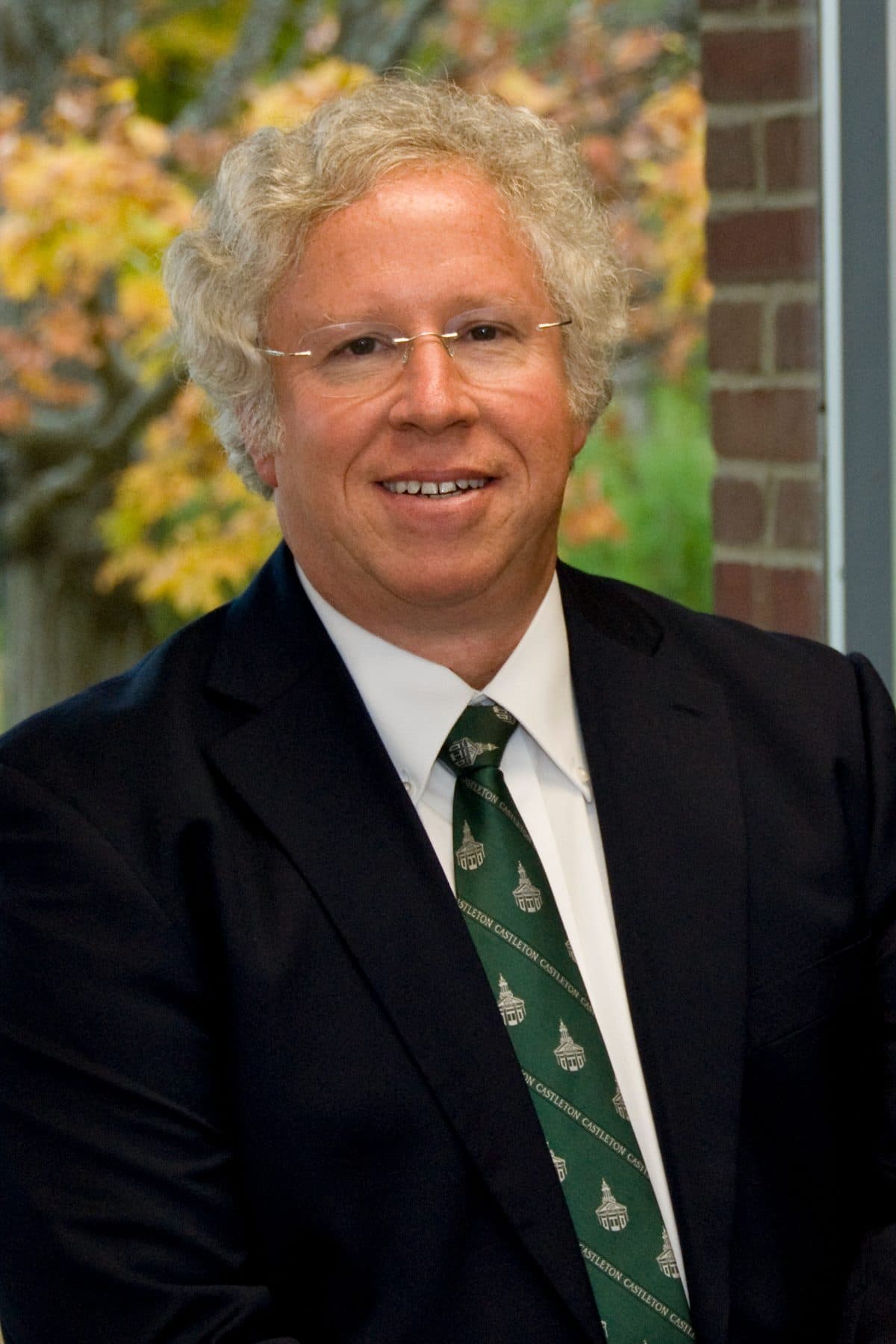 Portrait of Dave Wolk in a Castleton tie with autumn foliage behind him.