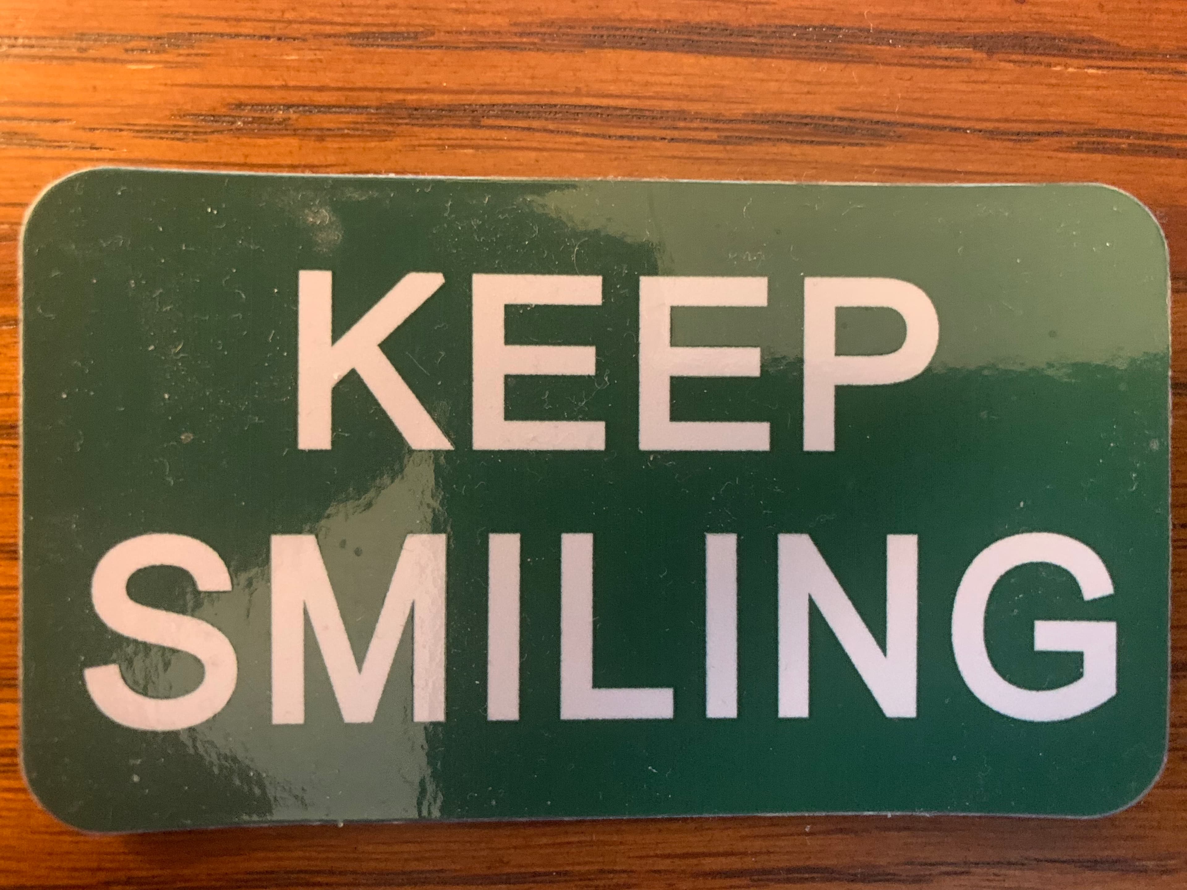 A green “Keep Smiling” campaign magnet.